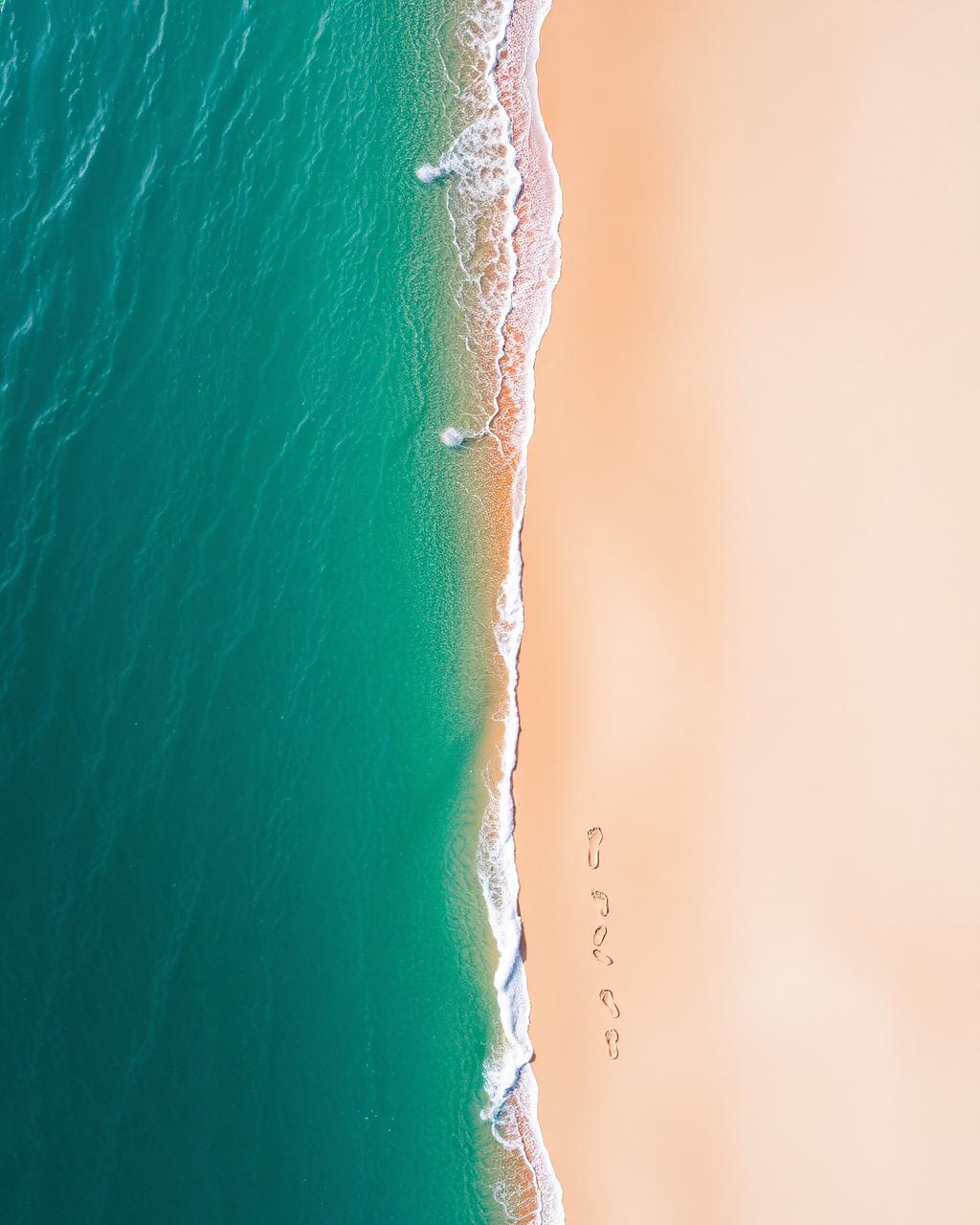 Aerial of turquoise sea meeting sand